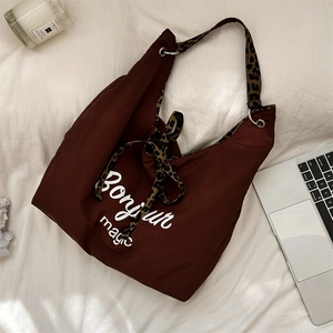 Flat lay of brown hobo tote bag with leopard print strap and Bonjour Magic print
