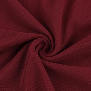 Détail macro du tissu en maille rouge vin montrant la texture fine et la structure respirante