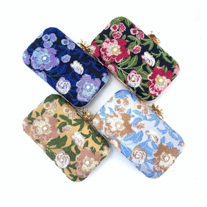 Top view of four floral embroidered evening clutch bags with golden bow clasps on white base