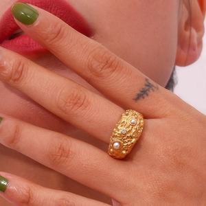 Close-up of gold lava texture ring with pearls and diamonds on woman hand