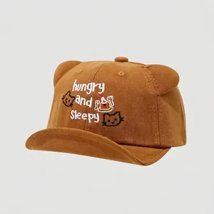 Detalle de gorra infantil de algodón marrón con orejas de oso y bordado decorativo suave