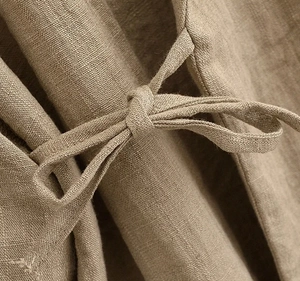 Macro view showing the knot tie detail and natural linen texture of khaki trousers