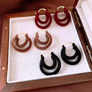 Close-up of double-circle velvet earrings in red, brown, and black with gold clasps