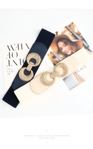 Flat lay of navy and beige elastic waist belts with round gold buckles and fashion magazines