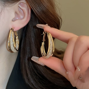 Detailed view of layered gold water-drop hoop earrings with shimmering glitter texture