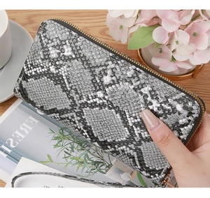Detail view of snakeskin pattern leather clutch with gold zipper and wrist strap