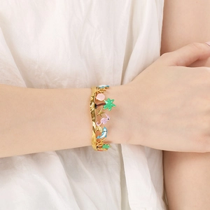 Macro shot of gold stainless steel ocean bracelet with colorful enamel charms on wrist