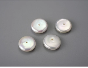 Detailed macro view of four white flat round freshwater pearls with high luster