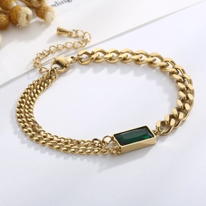 Close-up of a gold double-layer bracelet with a rectangular emerald green gemstone