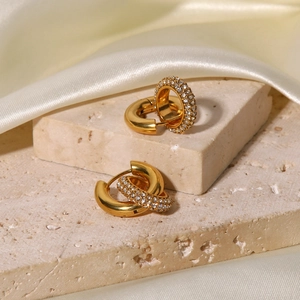 Detailed shot of gold plated hoop earrings with shimmering rhinestones on silk fabric
