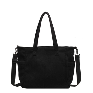Large black corduroy tote bag with dual handles and adjustable strap on white background