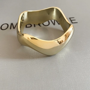 Détail macro d'une bague dorée ondulée avec finition polie sur une texture de cuir