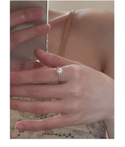 Detailed close-up of a vintage gold ring featuring a round white pearl on a hand