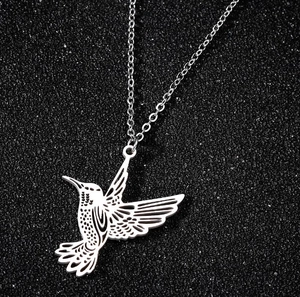 Macro shot of silver hummingbird pendant with hollow design on black textured surface