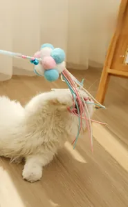 Cat chasing a feather wand with colorful plush balls and small metal bells