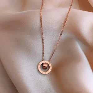 Detailed close-up of rose gold titanium necklace featuring Roman numeral ring and zircon stone