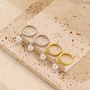 Detailed view of S925 silver and gold pearl hoop earrings with micro-set stones on travertine