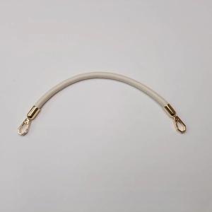 Close-up of cream leather handbag strap with golden metal clasps on grey background