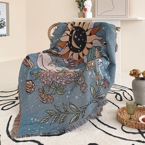 Detail of bohemian sun and moon woven blanket with tassel edges on a rattan chair