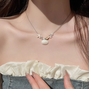 Nahaufnahme einer Sommerhalskette mit weißen Muscheln, Seestern und Perlen am Hals