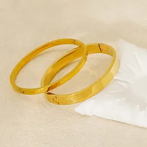 Polished 18K gold-plated stainless steel bangle set with smooth finish on beige surface
