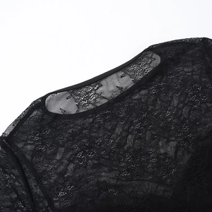 Gros plan sur le décolleté en dentelle florale et les coutures d'épaule d'un chemisier noir