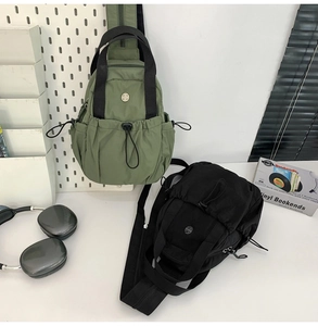 Detail of army green and black nylon sling bags with drawstring pockets and double handles