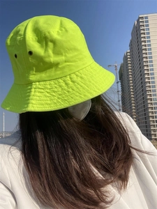 Detailed outdoor shot of neon green cotton bucket hat with washed texture and wide brim