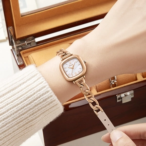 Montre carrée or rose avec cadran nacré et bracelet chaîne en cuir porté au poignet