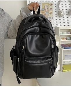 Detail of black leather backpack showing durable top handle and multi-layer zipper pockets