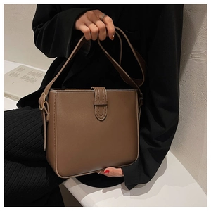 Detail view of smooth dark brown PU leather bucket bag with vertical strap and metal buckle