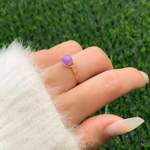 Macro shot of handmade wire wrapped ring featuring natural purple gemstone and gold wire
