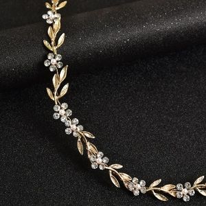 Détail du bandeau de mariée avec feuilles dorées, strass brillants et perles blanches