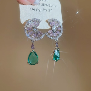 Detail of silver drop earrings with green pear-shaped zircon and purple stone accents