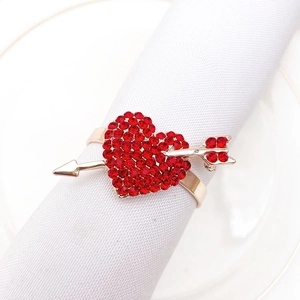 Macro shot of gold metal heart napkin ring with red rhinestones on white napkin