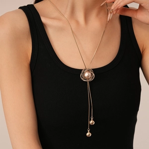 Détail d'un collier long doré avec pendentif fleur en strass et perle à pompons élégant