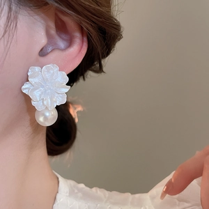 Detail shot of elegant floral earrings featuring white resin petals and a pearl drop