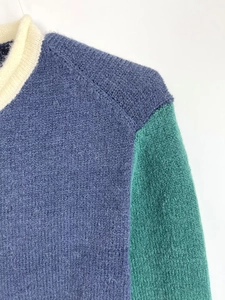 Detail of color-block knit sweater featuring navy blue body and emerald green shoulder