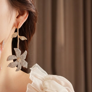 Exquisite gold long flower drop earrings with white rhinestones on a model side view