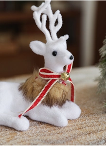 Close-up of a white flocked Christmas reindeer figurine with red bow and gold bell detail