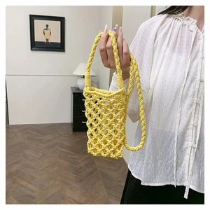 Handmade woven cotton mobile phone bag in bright yellow being held by a model