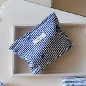 Detail of blue and white plaid makeup bag with floral embroidery and simple wish label