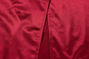 Macro detail of wine red satin evening dress showing smooth texture and fine stitching