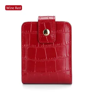 Detail view of wine red crocodile pattern leather pouch with gold metal clasp and mirror
