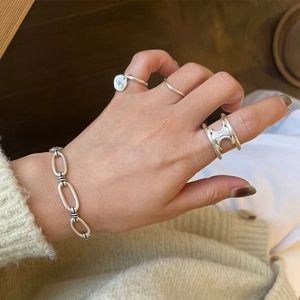 Detailed view of vintage silver chain bracelet and layered rings on model hand