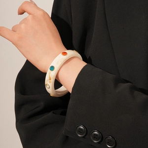 Detailed close-up of acrylic marble bangle with multi-colored rhinestones on model