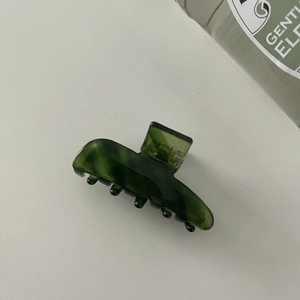 Detail view of a dark green translucent hair claw clip with a glossy acetate finish
