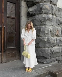Detail of white V-neck linen set with puff sleeves and A-line skirt in outdoor scenery