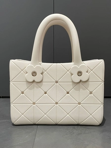 Dettaglio borsa tote bianca in EVA con trama a rombi e ciondoli floreali decorativi