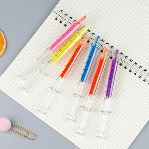 Set of six syringe-shaped highlighters in vibrant neon colors on a grid notebook